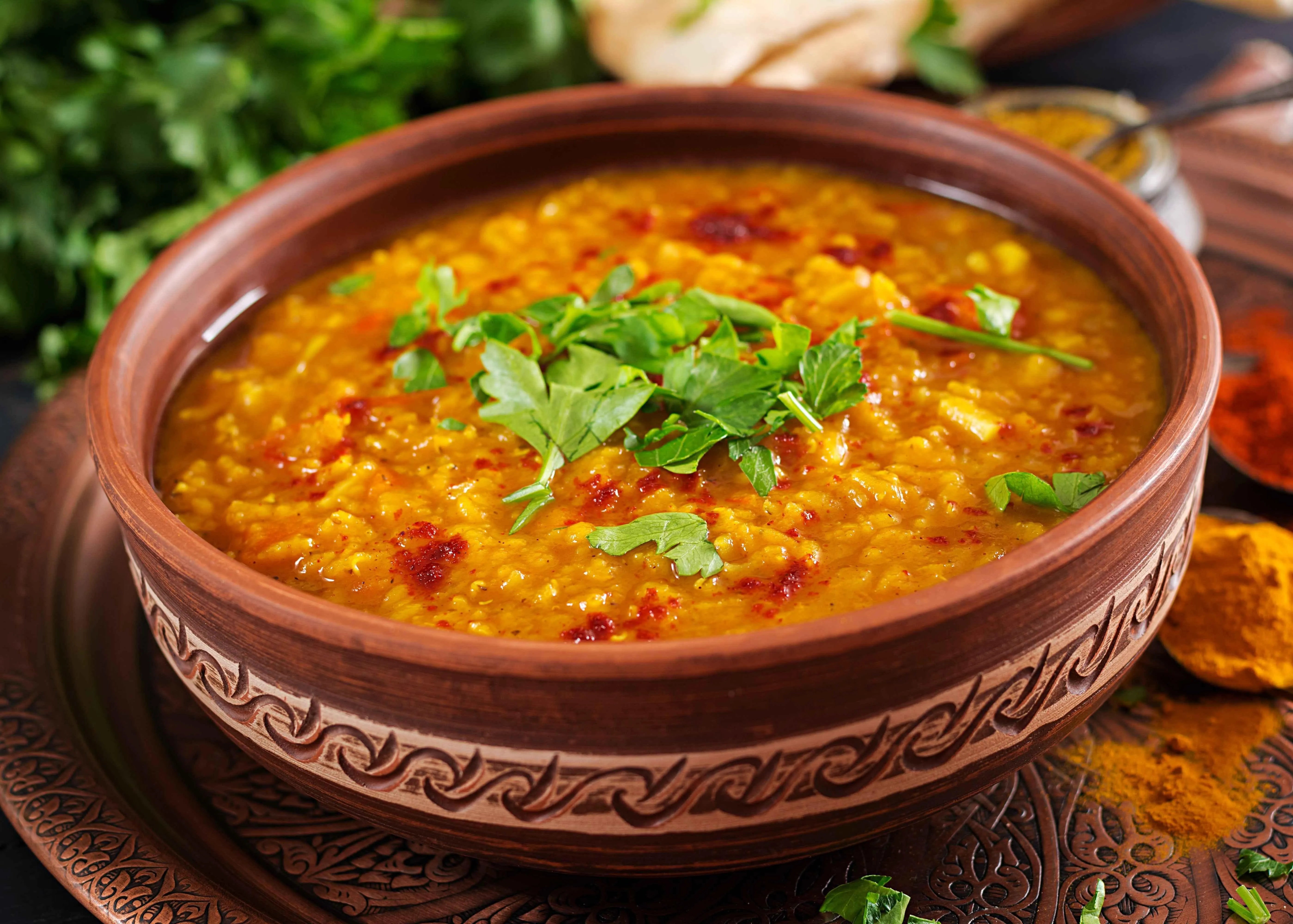 Traditional Indian dal in a clay bowl, garnished with fresh cilantro and spices